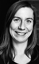 Monika Esterer Ein Porträt einer lächelnden Frau mit langen, glatten Haaren. Sie trägt ein schwarzes Oberteil und hat einen freundlichen Ausdruck. Der Hintergrund zeigt eine strukturierte Wand.